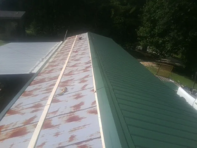 Old rusted panels beside newly installed green metal roofing — Wind Damage Roof Repair by Roofing Brothers in East Vandergrift