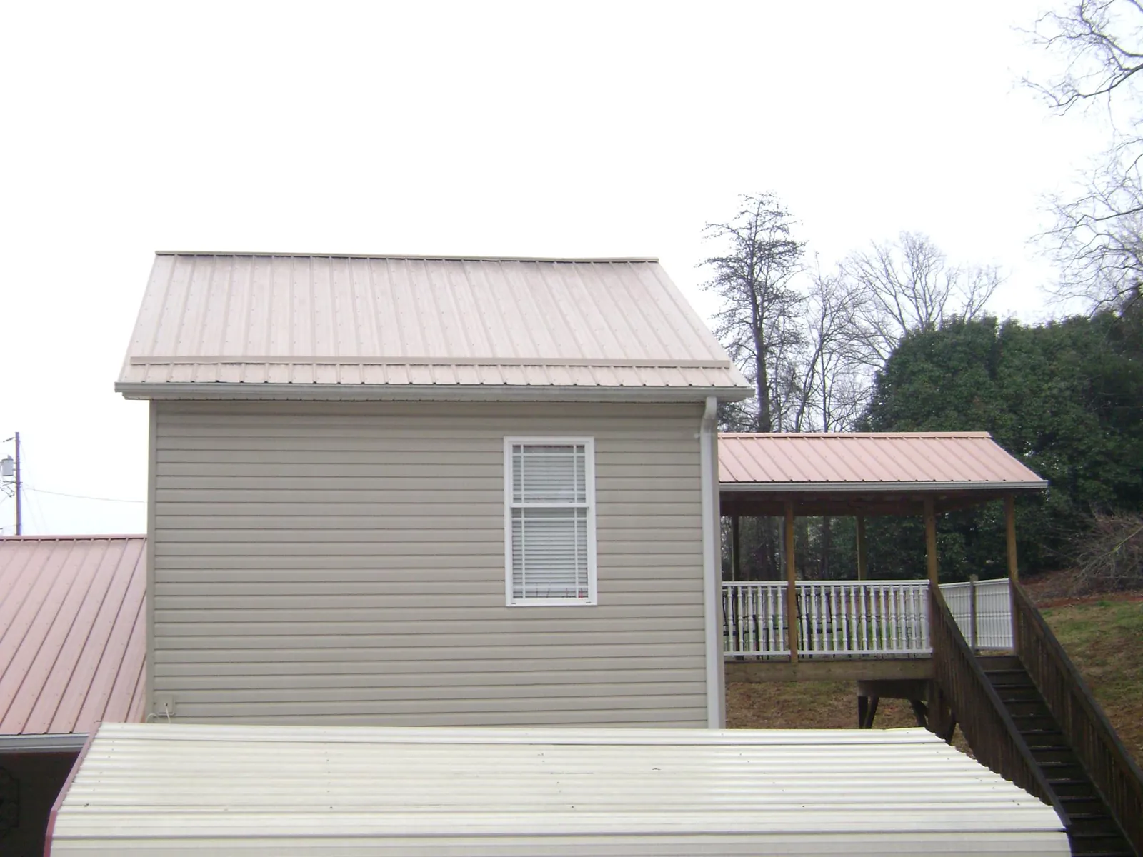Tan metal roofs on a two story addition and attached porch, from a Roof Replacement job in East Vandergrift