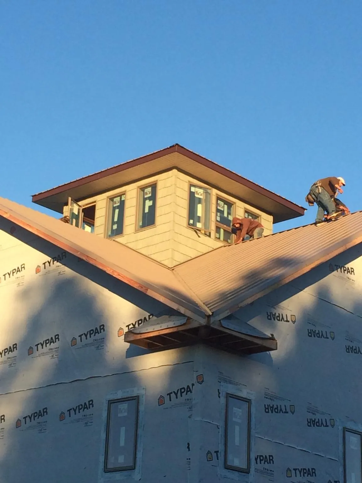 Roofers working around a rooftop cupola on a new metal roof at sunset — Roof Waterproofing in East Vandergrift by Roofing Brothers
